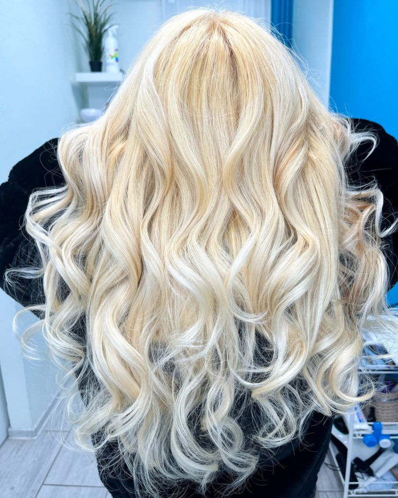 Păr blond deschis, aranjat în bucle ample.
